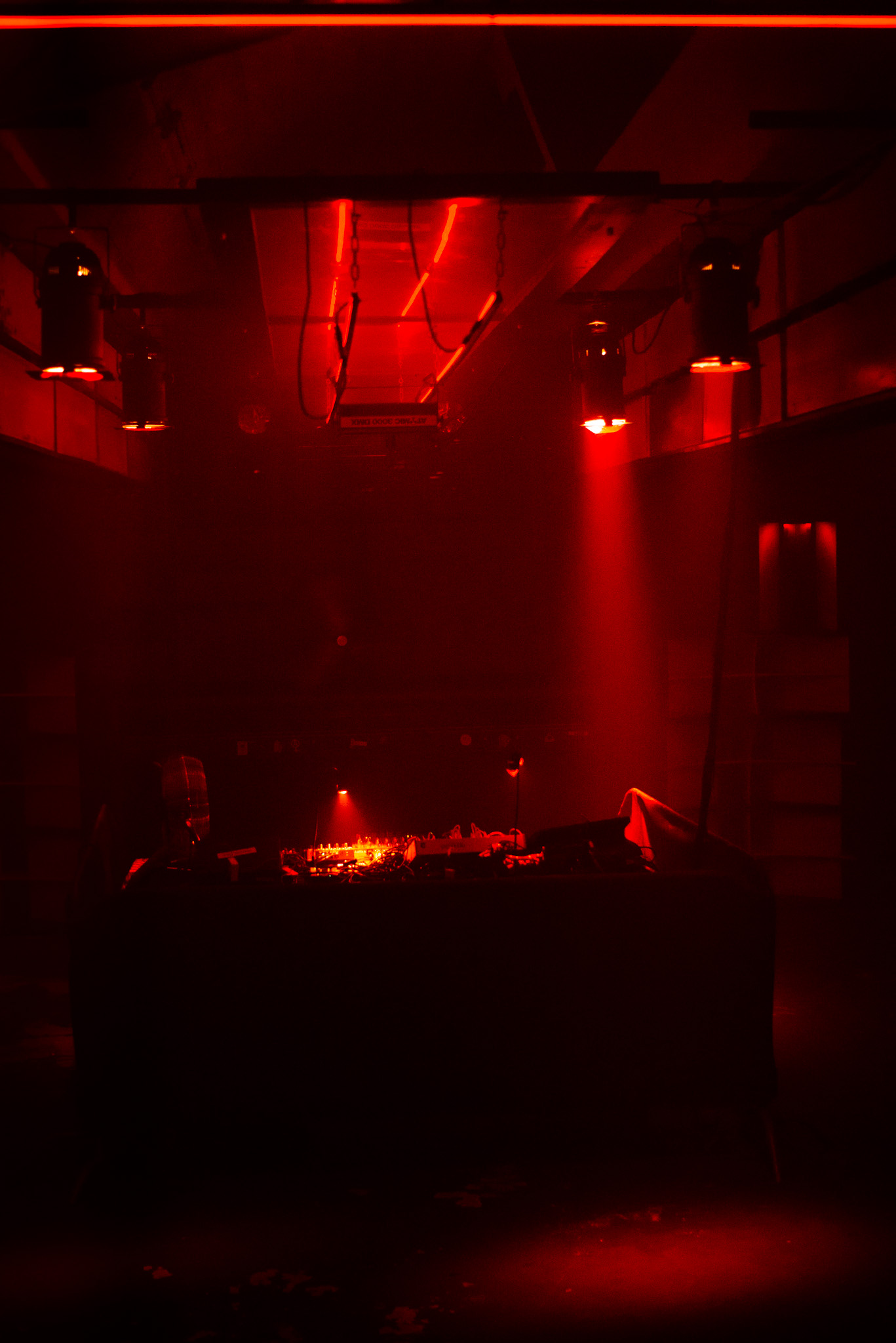 Red-lit DJ booth from the back of the room